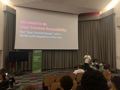 Craig speaks on the Front End North stage beside a slide reading "We need to do User Centred Accessibility — not User Centred Design with a WCAG audit slapped on at the end."