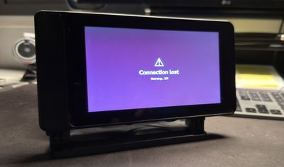The kiosk showing its offline screen: a warning triangle with Connection lost, retrying 2 of 5. After 5 failures the watchdog reboots the Pi automatically.