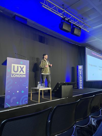 A wide shot of the UX London stage as Craig presents a slide titled "Make links easy to identify", comparing an obvious underlined link with one that is harder to spot.