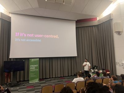 Craig stands beside a slide declaring "If it's not user-centred, it's not accessible!" at Front End North.