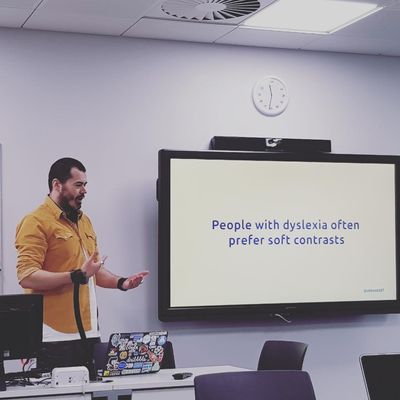 Craig gestures beside a screen reading "People with dyslexia often prefer soft contrasts", shown as dark blue text on a soft cream background.
