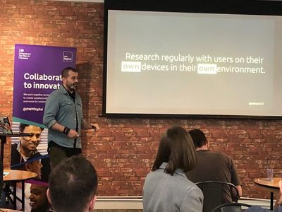 Craig presents in front of a brick wall and a DWP Digital banner, beside a slide reading "Research regularly with users on their own devices in their own environment".